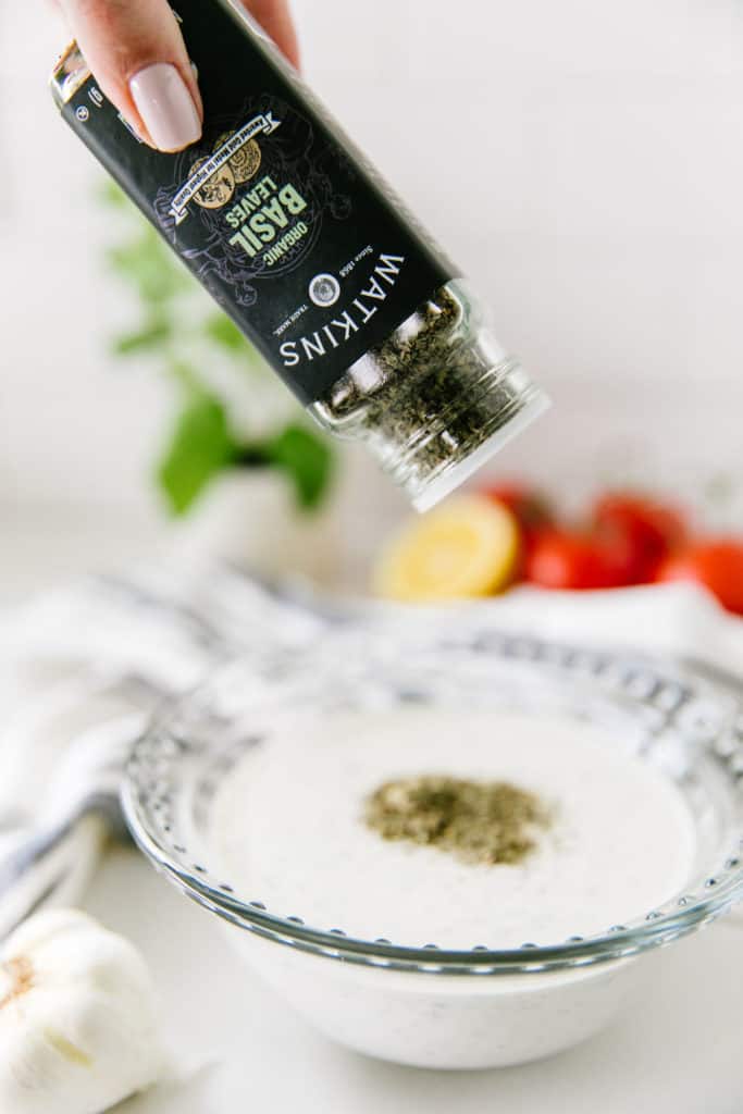 The Best Homemade Ranch Dressing- adding Watkins basil to a bowl