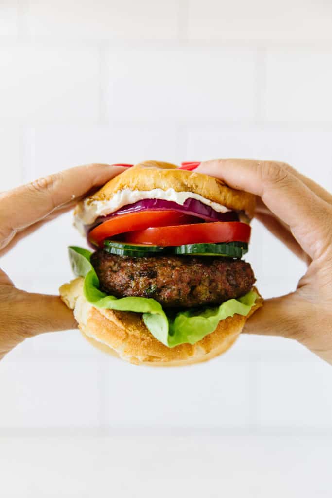 Mediterranean lamb burger held in hands ready to eat