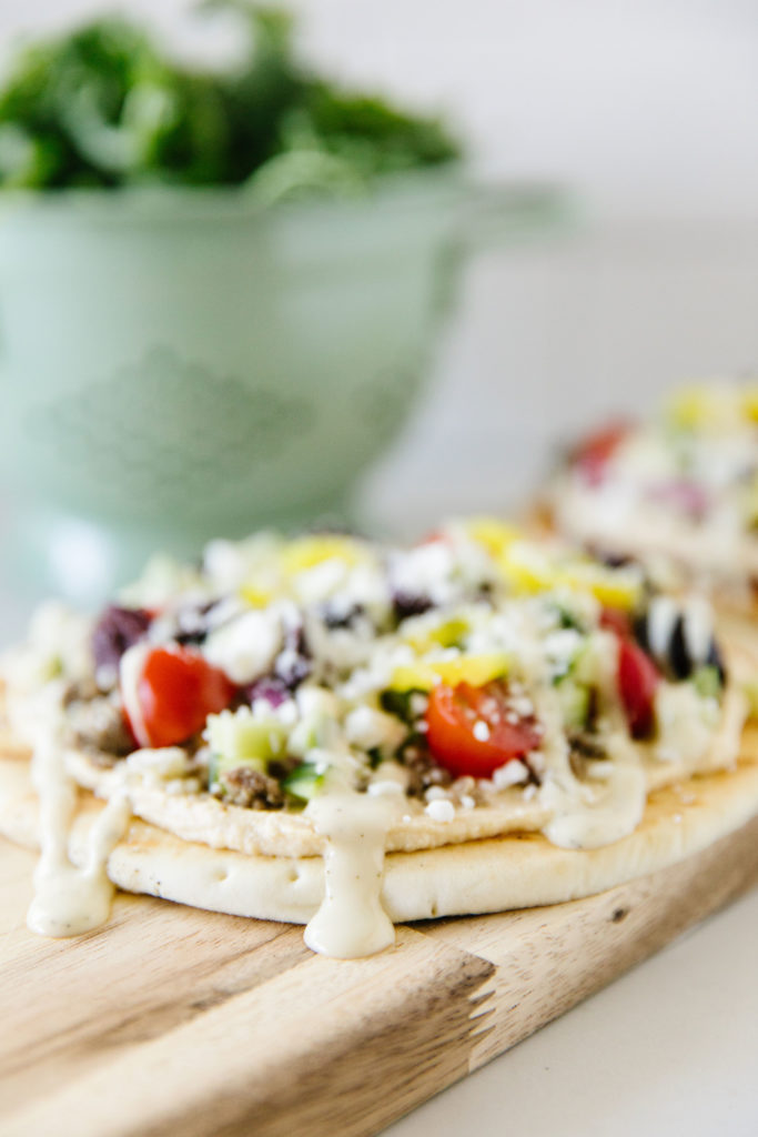 Grilled Greek pita pizzas with drizzled dressing 